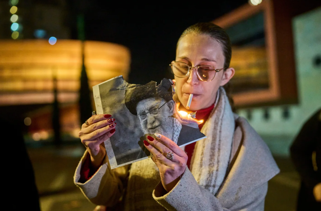 A demonstrator lights a cigarette with a burning poster depicting Supreme Leader Ayatollah Ali Khamenei