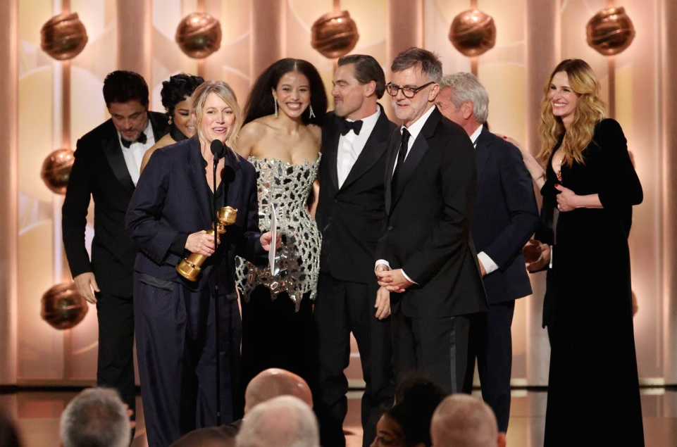 This image released by CBS Broadcasting shows Sara Murphy, foreground left, appearing with writer-director Paul Thomas Anderson, foreground right, and other cast members, as well as presenter Julia Roberts, right, as they accept the award for best motion picture - musical or comedy for “One Battle After Another” during the 83rd Golden Globes on Sunday, Jan. 11, 2026, at the Beverly Hilton in Beverly Hills, Calif. (Kevork Djansezian/CBS Broadcasting via AP)
